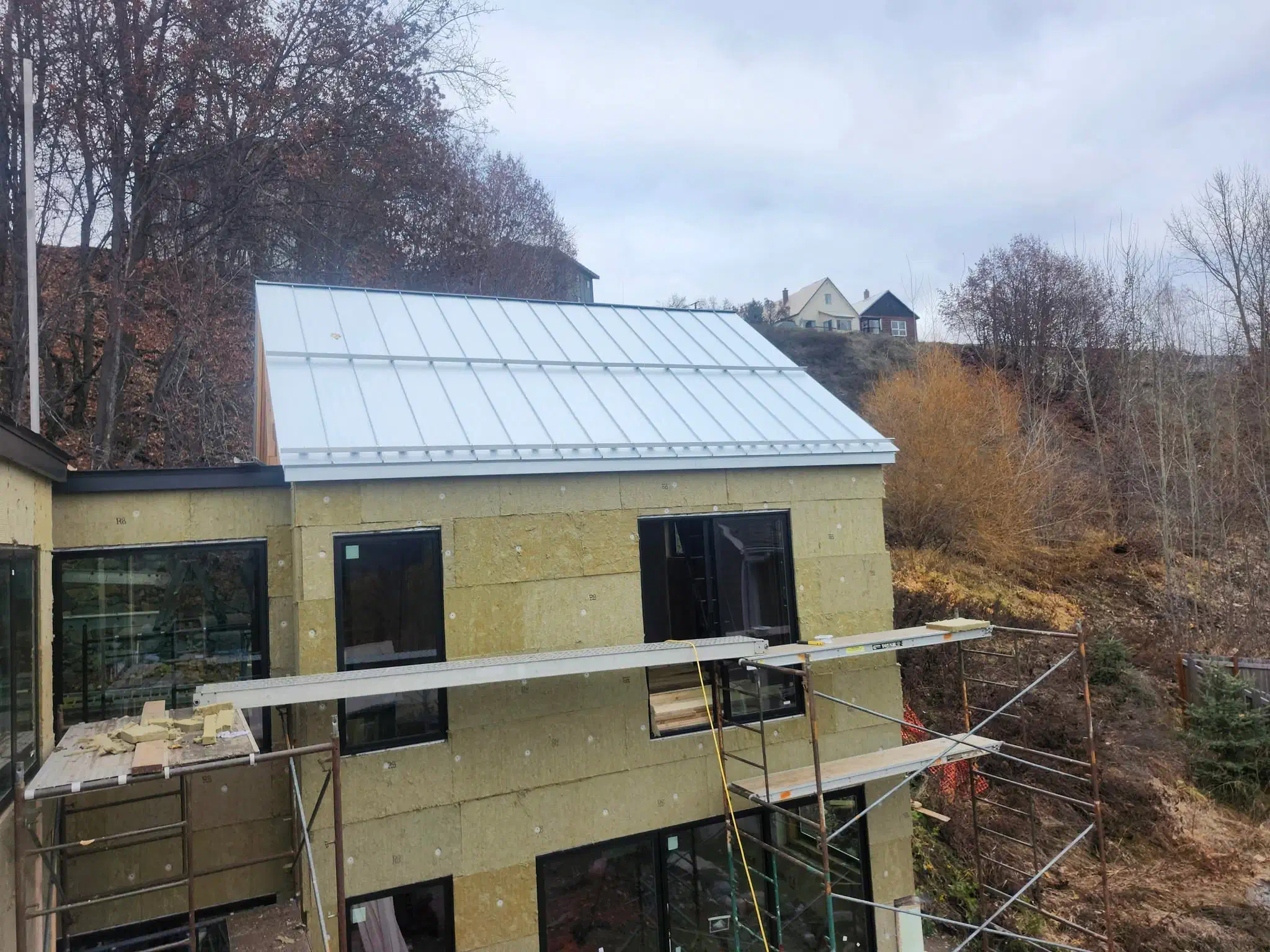 Completed standing seam metal roof on a modern hillside home — West Kootenays