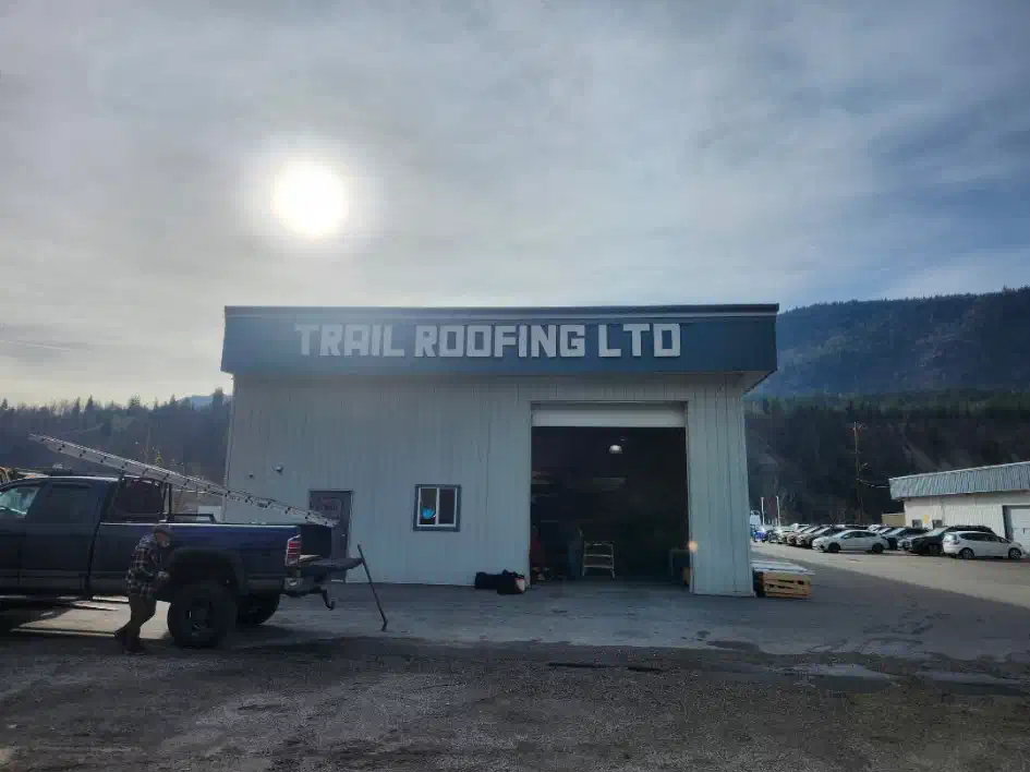Trail Roofing Ltd shop building with signage over an open bay door and a ladder-rack pickup out front — West Kootenays