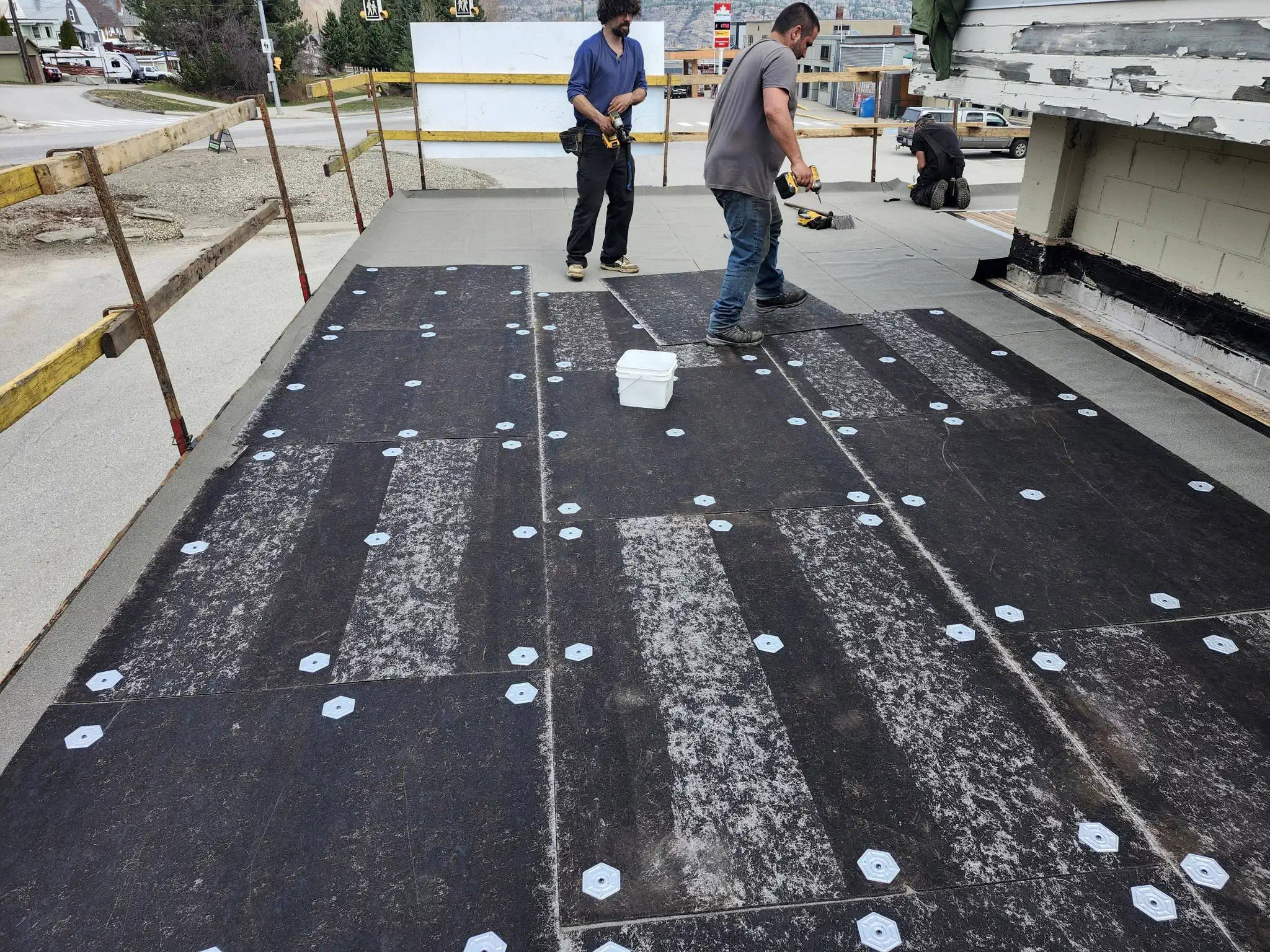 Base sheet fastened with seam plates on a flat roof before the torch-on cap sheet goes down — West Kootenays