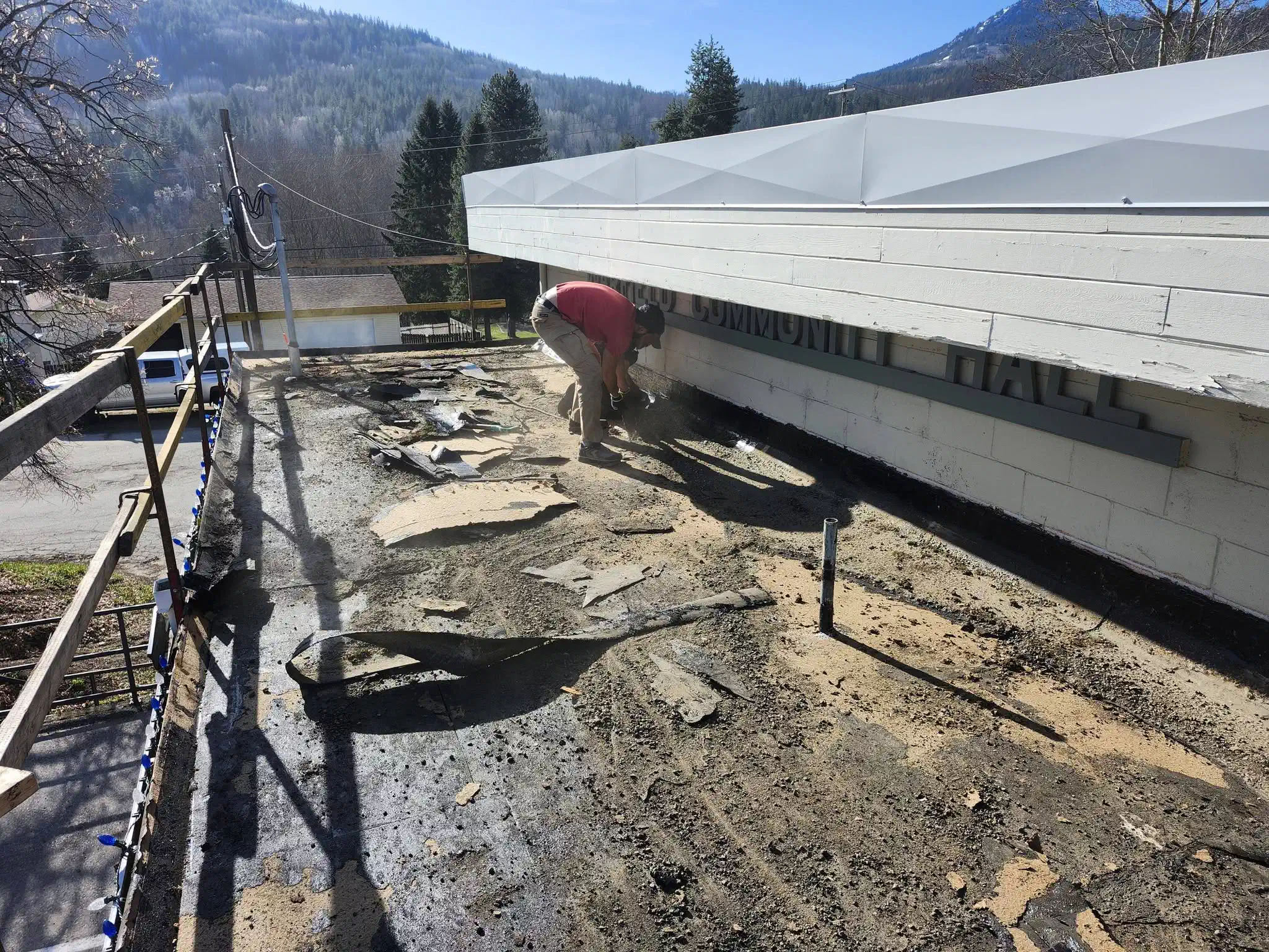 Tear-off underway on a community hall flat roof — West Kootenays
